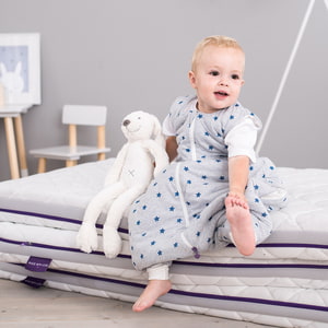 Kind auf Matratzenstapel im Träumeland Ganzjahres Schlafanzug TO GO