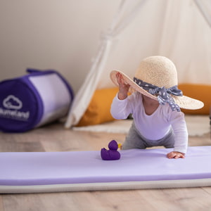 Baby mit Hut auf Reisematratze