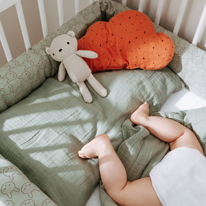 Babyfüße im Bett mit Musselin Bettwäsche