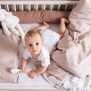 Baby im Bett mit kuscheliger Bettschlange